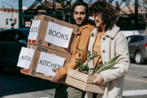 Man and Woman Holding Boxes of Books