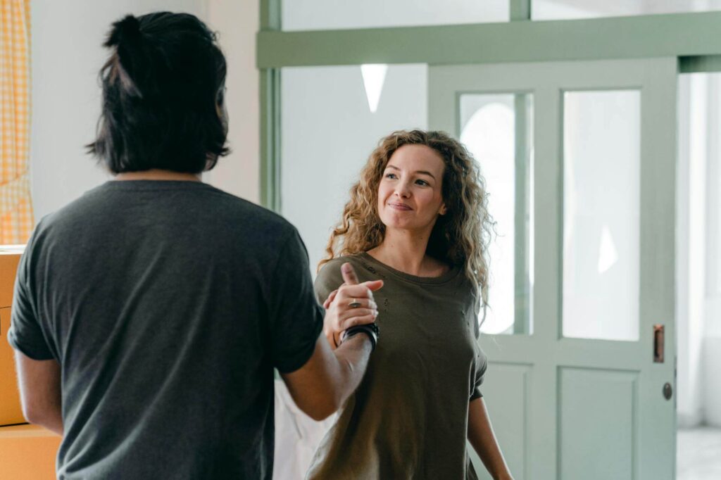 Happy couple shaking hands in apartment