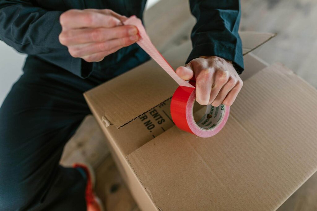 Man Packing Box with Red Tape